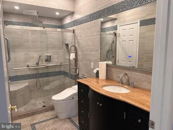 a bathroom with a granite countertop shower sink vanity mirror and toilet