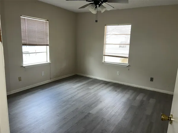 a view of an empty room with a window and wooden floor