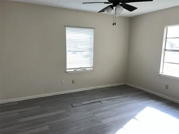 an empty room with a window and a fan