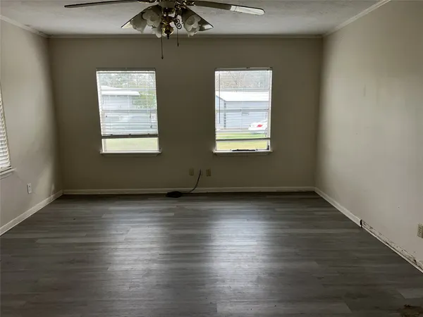 an empty room with wooden floor and windows