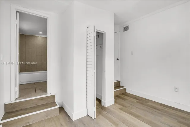 an empty room with wooden floor and entrance