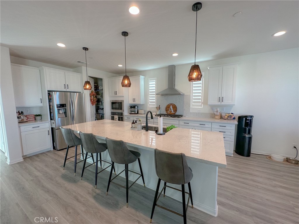 39547 Verbena Way Temecula, CA 92591 - Photo 2 of 31 a kitchen with stainless steel appliances kitchen island granite countertop a table chairs and a refrigerator