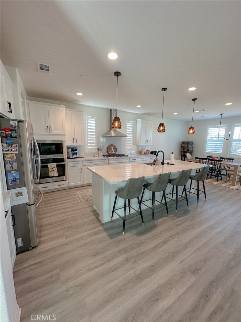 39547 Verbena Way Temecula, CA 92591 - Photo 3 of 31 a kitchen with stainless steel appliances kitchen island granite countertop a table chairs and a refrigerator