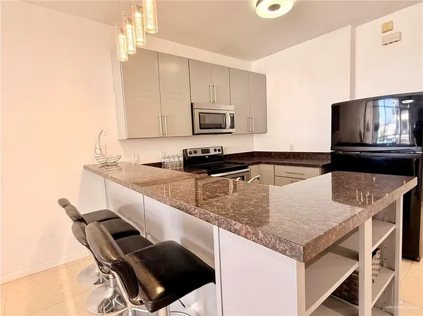 a view of kitchen with stainless steel appliances kitchen island granite countertop a sink cabinets and window