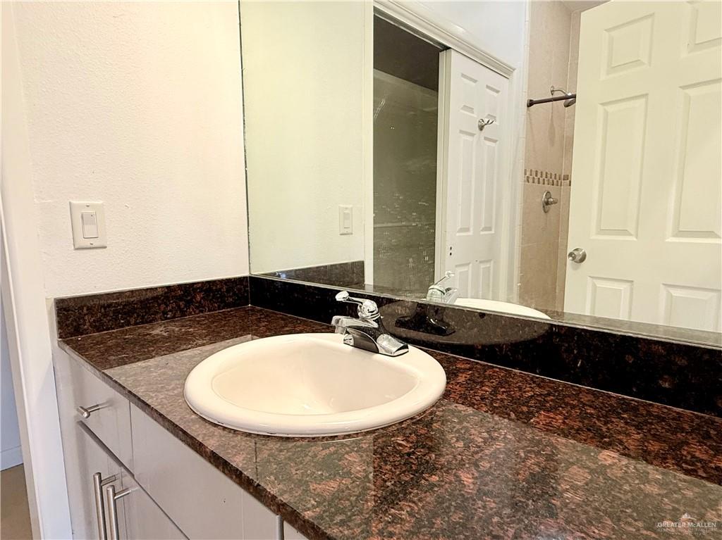 813 Travis Street, Unit 207 Mission, TX 78572 - Photo 21 of 38 a bathroom with a granite countertop sink and a mirror