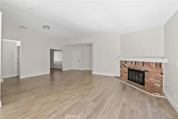 an empty room with wooden floor fireplace and windows