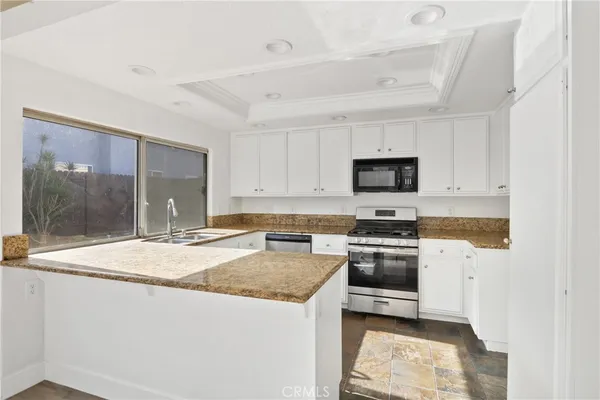 a kitchen with stainless steel appliances granite countertop a stove a sink and a microwave