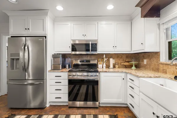 a kitchen with stainless steel appliances granite countertop a refrigerator and a stove