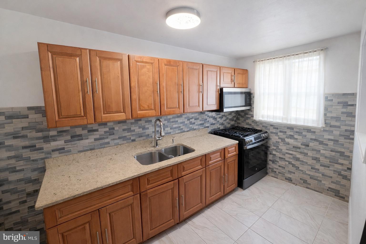 1305 Robbins Street Philadelphia, PA 19111 - Photo 5 of 19 a kitchen with granite countertop a sink stove and cabinets