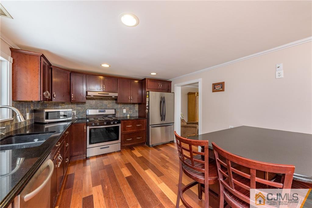 148 Rolling Ridge Road West Milford, NJ 07480 - Photo 8 of 25 a kitchen with stainless steel appliances granite countertop a stove top oven a sink dishwasher a dining table and chairs with wooden floor