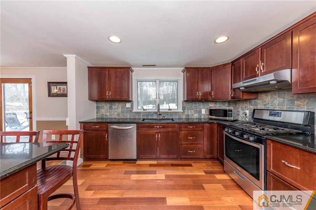 148 Rolling Ridge Road West Milford, NJ 07480 - Photo 9 of 25 a kitchen with stainless steel appliances granite countertop a stove top oven a sink dishwasher a dining table and chairs with wooden floor