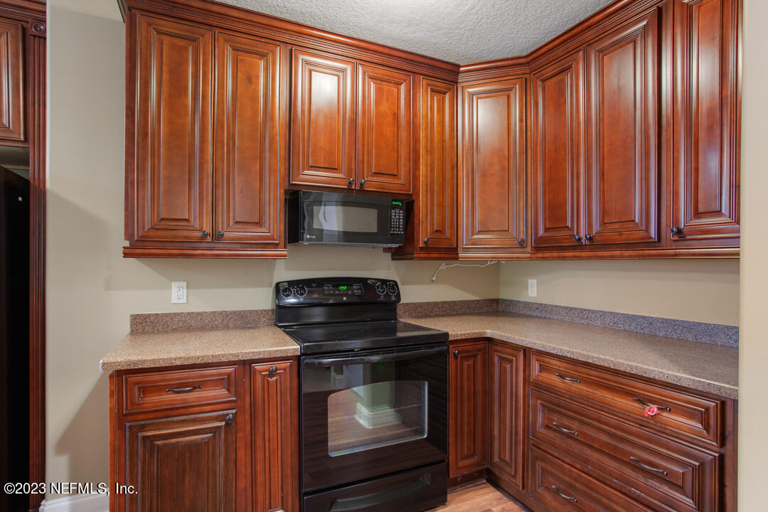3165 Ravines Road, Unit 3604 Middleburg, FL 32068 - Photo 4 of 16 a kitchen with wooden cabinets and a stove top oven