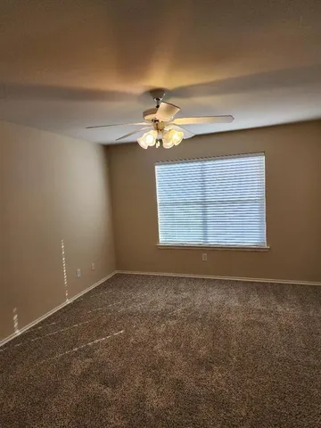 an empty room with windows and chandelier fan