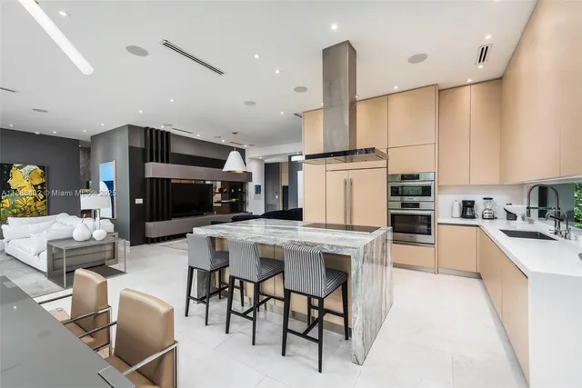 a kitchen with stainless steel appliances kitchen island granite countertop a table chairs and a refrigerator