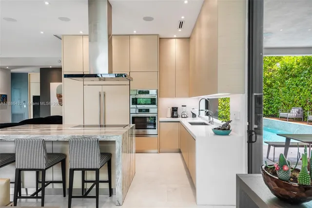 a kitchen with stainless steel appliances kitchen island granite countertop a table chairs and a refrigerator