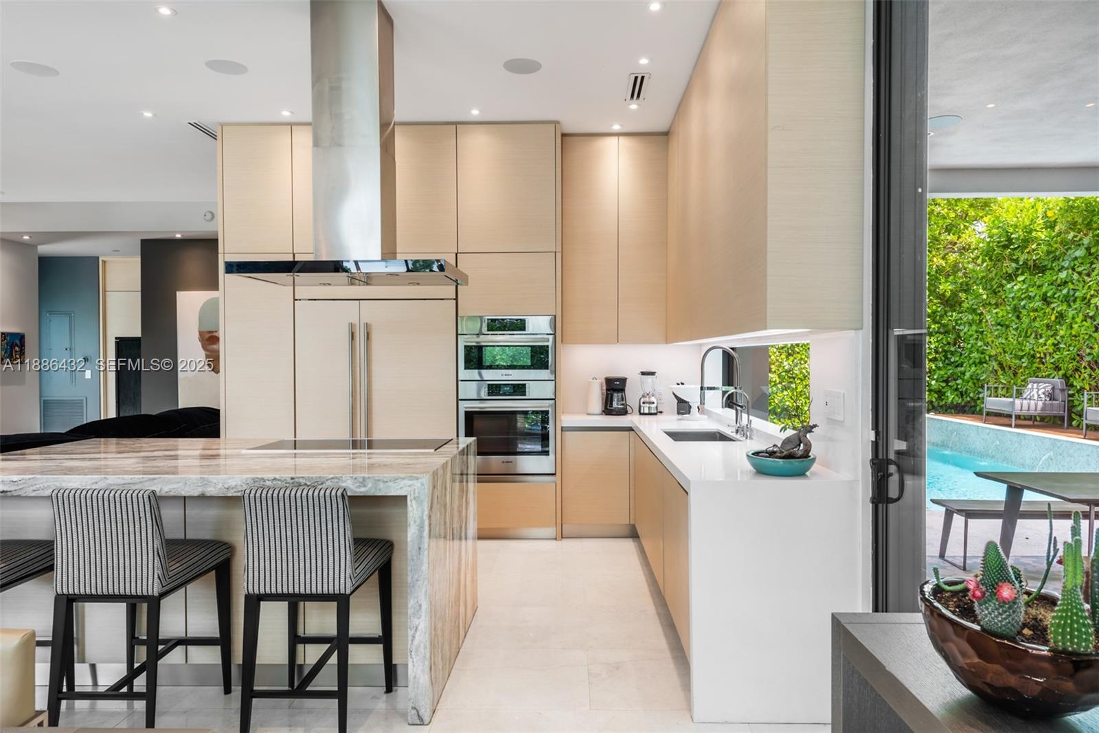 4675 Northeast 2nd Avenue Miami, FL 33137 - Photo 24 of 44 a kitchen with stainless steel appliances kitchen island granite countertop a table chairs and a refrigerator