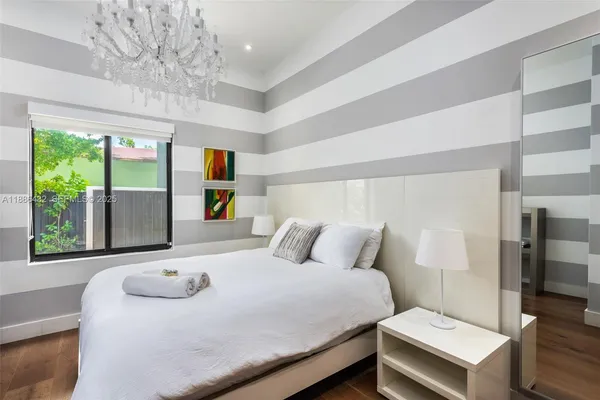 a bedroom with a bed and a large window with the potted plants