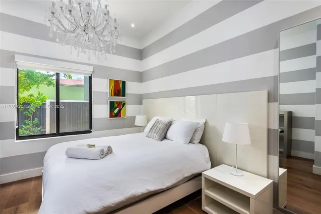 a bedroom with a bed and a large window with the potted plants