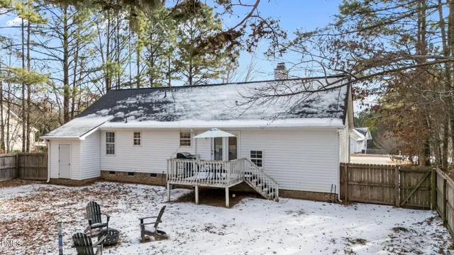 a view of a white house with a wooden bench and chair