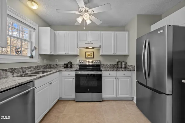 a kitchen with stainless steel appliances granite countertop a refrigerator sink and stove