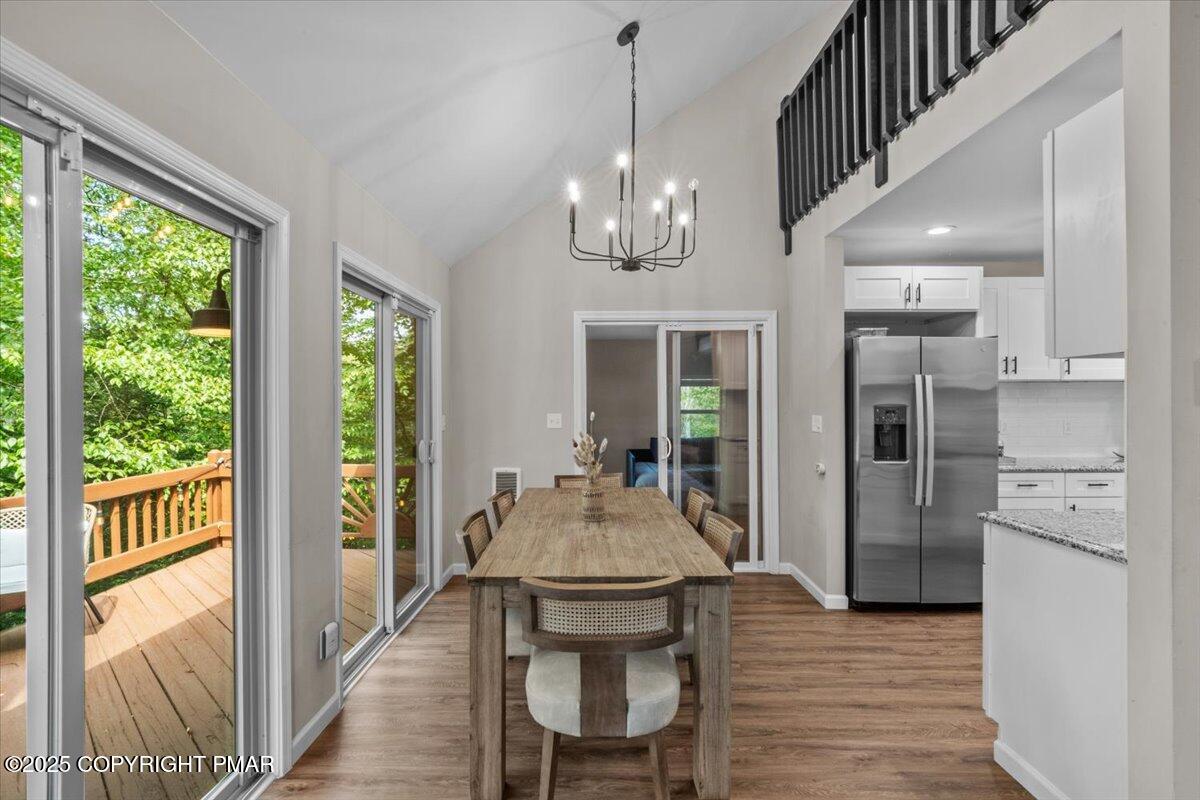 415 Canterbury Road Bushkill, PA 18324 - Photo 6 of 36 a dining room with wooden floor a chandelier a wooden table and chairs