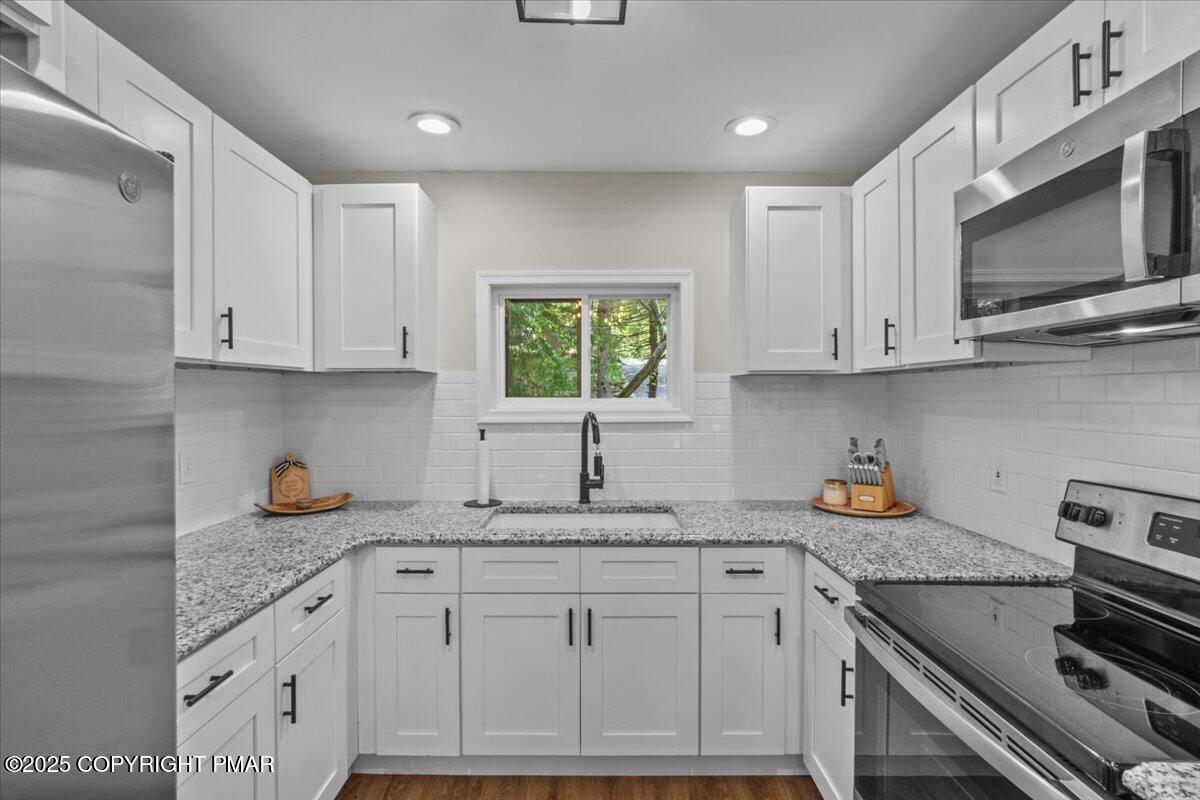 415 Canterbury Road Bushkill, PA 18324 - Photo 8 of 36 a kitchen with stainless steel appliances granite countertop a sink a stove a microwave a counter space and cabinets