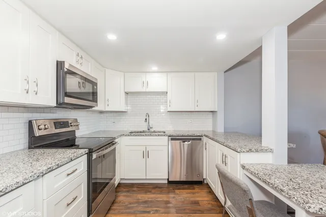 a kitchen with a refrigerator a sink and white cabinets