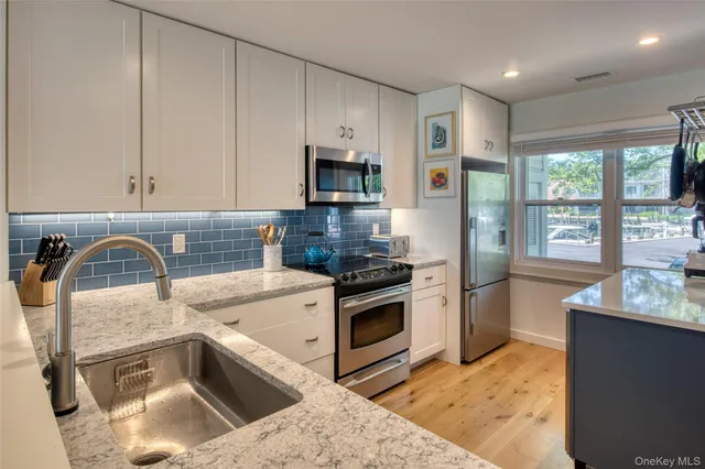 a kitchen with stainless steel appliances granite countertop a sink a stove and a refrigerator