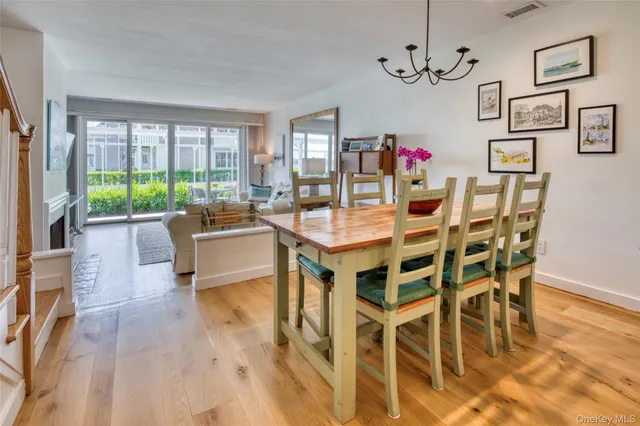 a dining room with wooden floor a chandelier a glass table and chairs