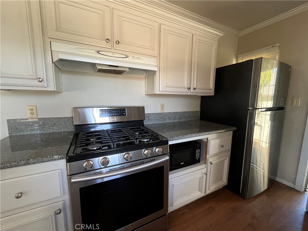 1026 5th Street Calimesa, CA 92320 - Photo 10 of 19 a kitchen with stainless steel appliances granite countertop white cabinets and a stove a refrigerator with wooden floors