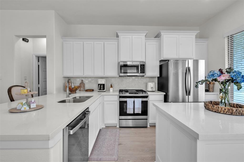 228 Palo Duro Bend Rhome, TX 76078 - Photo 7 of 35 a kitchen with refrigerator a sink and white cabinets