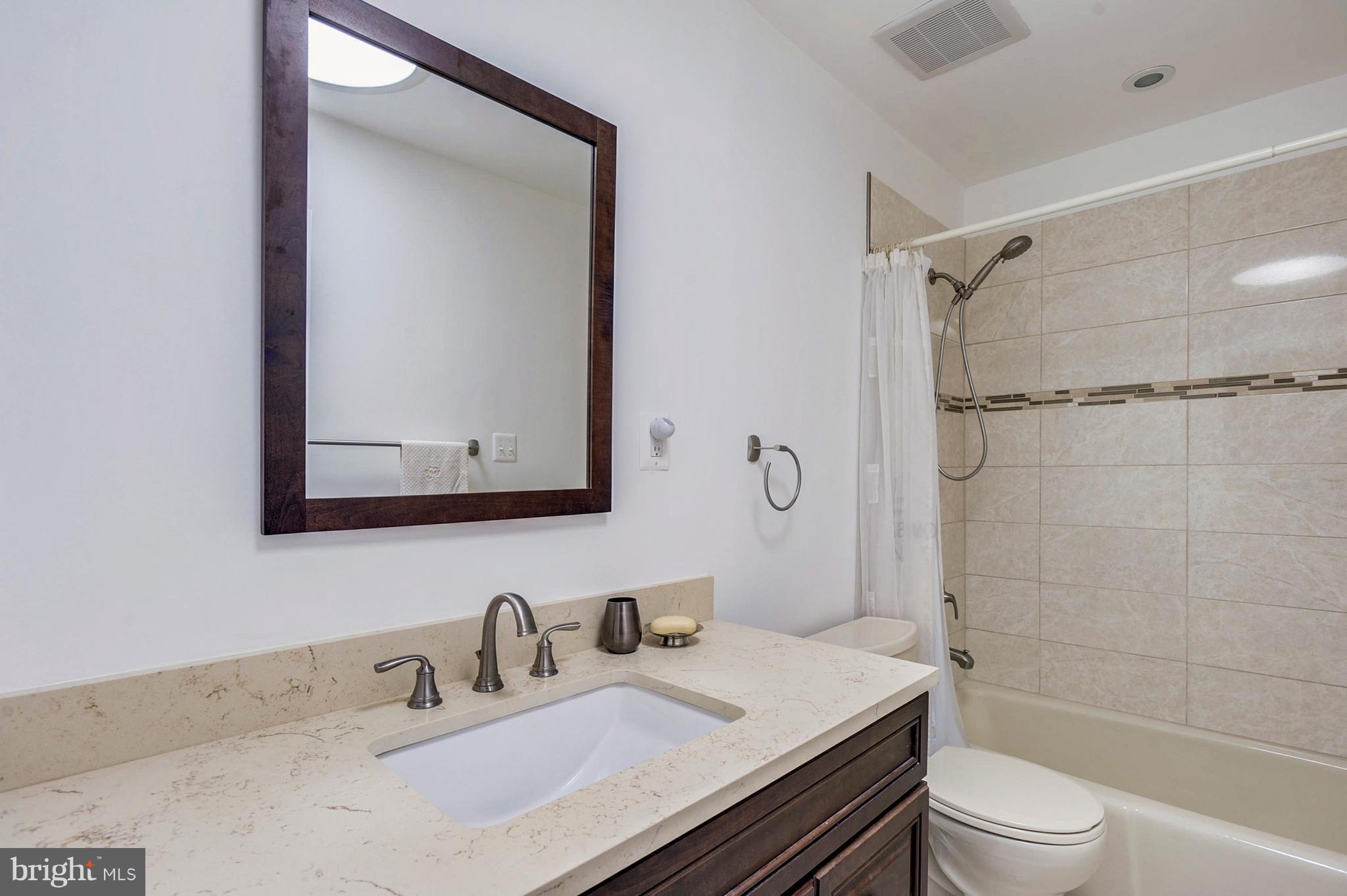 11796 Indian Ridge Road Reston, VA 20191 - Photo 16 of 30 a bathroom with a granite countertop sink toilet a mirror and shower