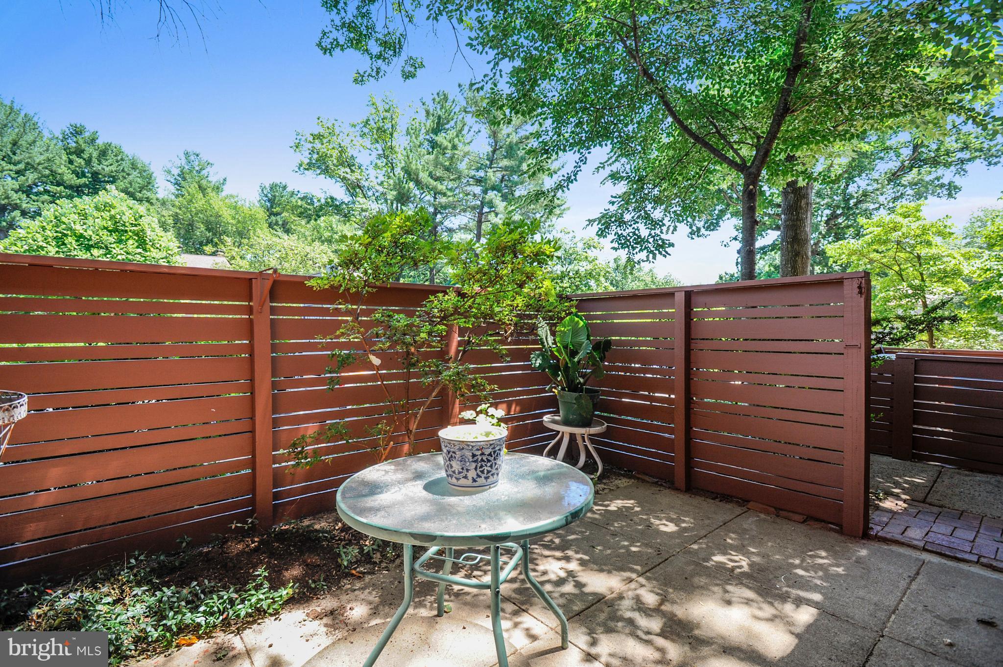 11796 Indian Ridge Road Reston, VA 20191 - Photo 6 of 30 a backyard of a house with table and chairs potted plants and wooden fence