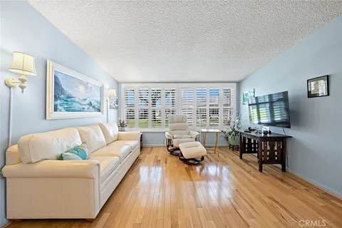 a living room with furniture floor to ceiling window and wooden floor