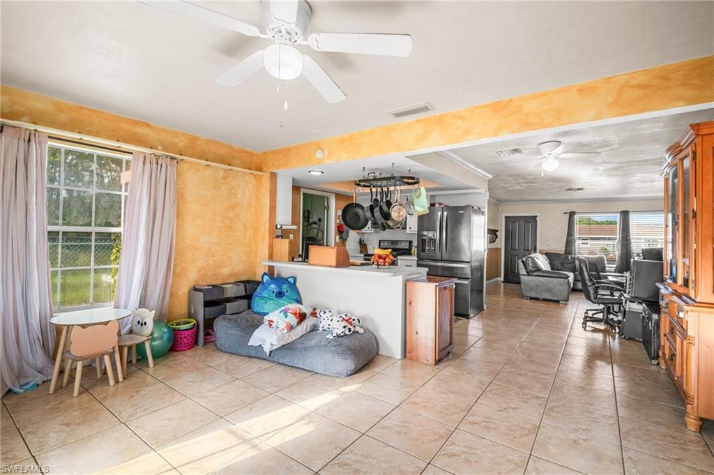 115 Georgia Road Lehigh Acres, FL 33936 - Photo 12 of 26 Kitchen featuring open floor plan, ceiling fan, appliances with stainless steel finishes, light tile patterned floors, and a peninsula