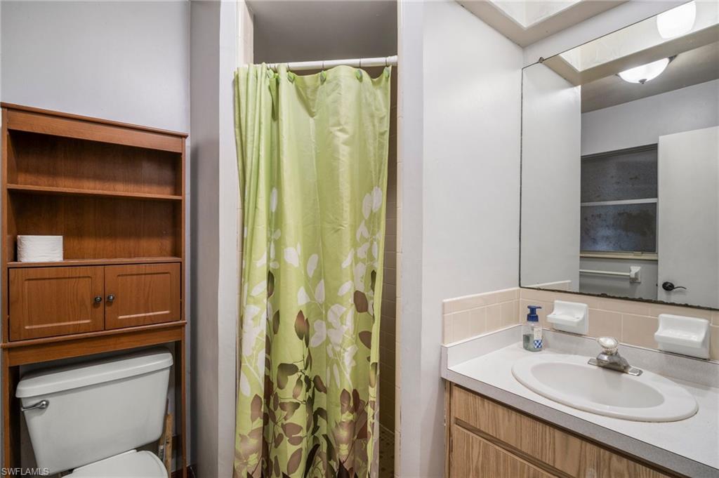 115 Georgia Road Lehigh Acres, FL 33936 - Photo 19 of 26 Bathroom featuring tasteful backsplash, toilet, vanity, and curtained shower