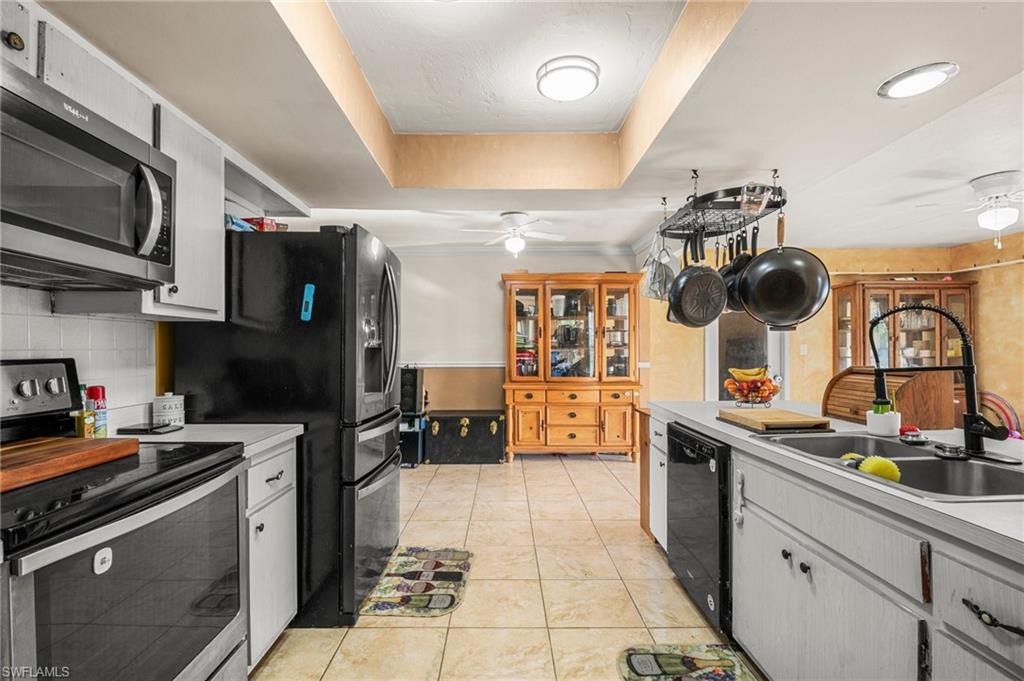 115 Georgia Road Lehigh Acres, FL 33936 - Photo 8 of 26 Kitchen with black appliances, ceiling fan, a sink, a raised ceiling, and light countertops