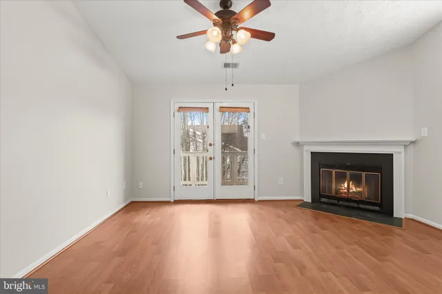 an empty room with windows fireplace and wooden floor