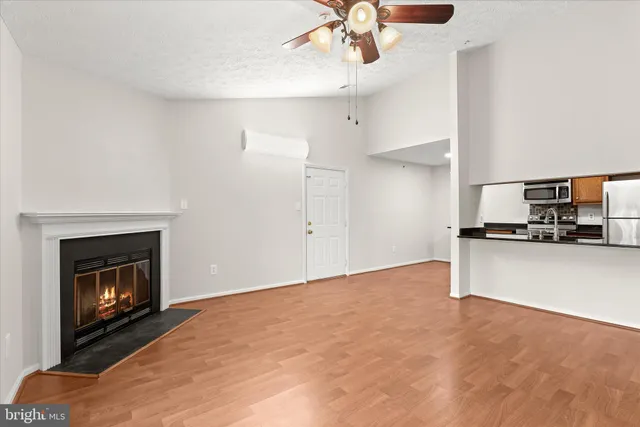 a view of empty room with kitchen fireplace and ceiling fan