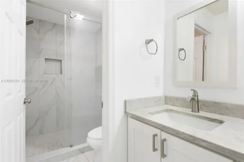 a bathroom with a granite countertop sink a toilet and shower