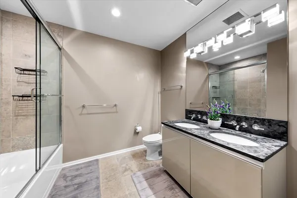a bathroom with a granite countertop sink a toilet a mirror and shower