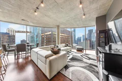 a living room with furniture floor to ceiling window and wooden floor