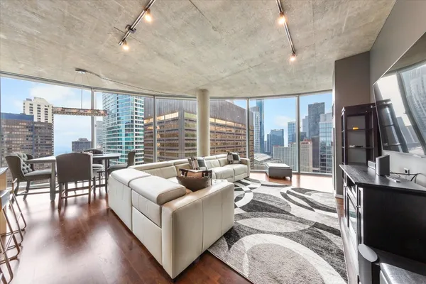 a living room with furniture floor to ceiling window and wooden floor
