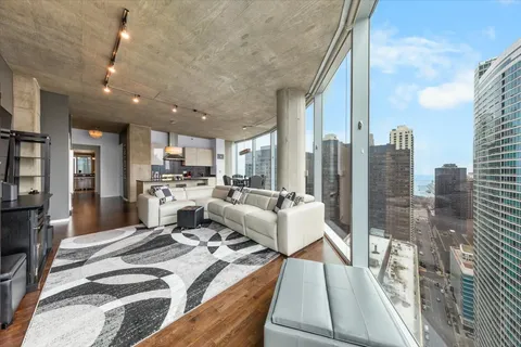 a living room with couches a coffee table and kitchen view with wooden floor