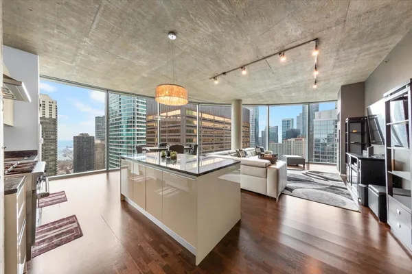 a large living room with stainless steel appliances kitchen island granite countertop a large window and a kitchen view