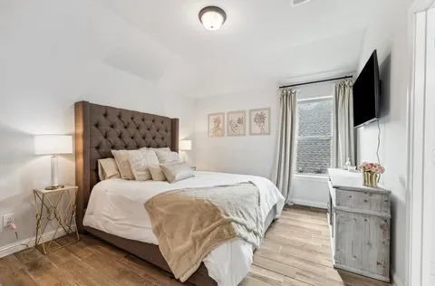 a bedroom with a large bed and a flat tv screen on dresser