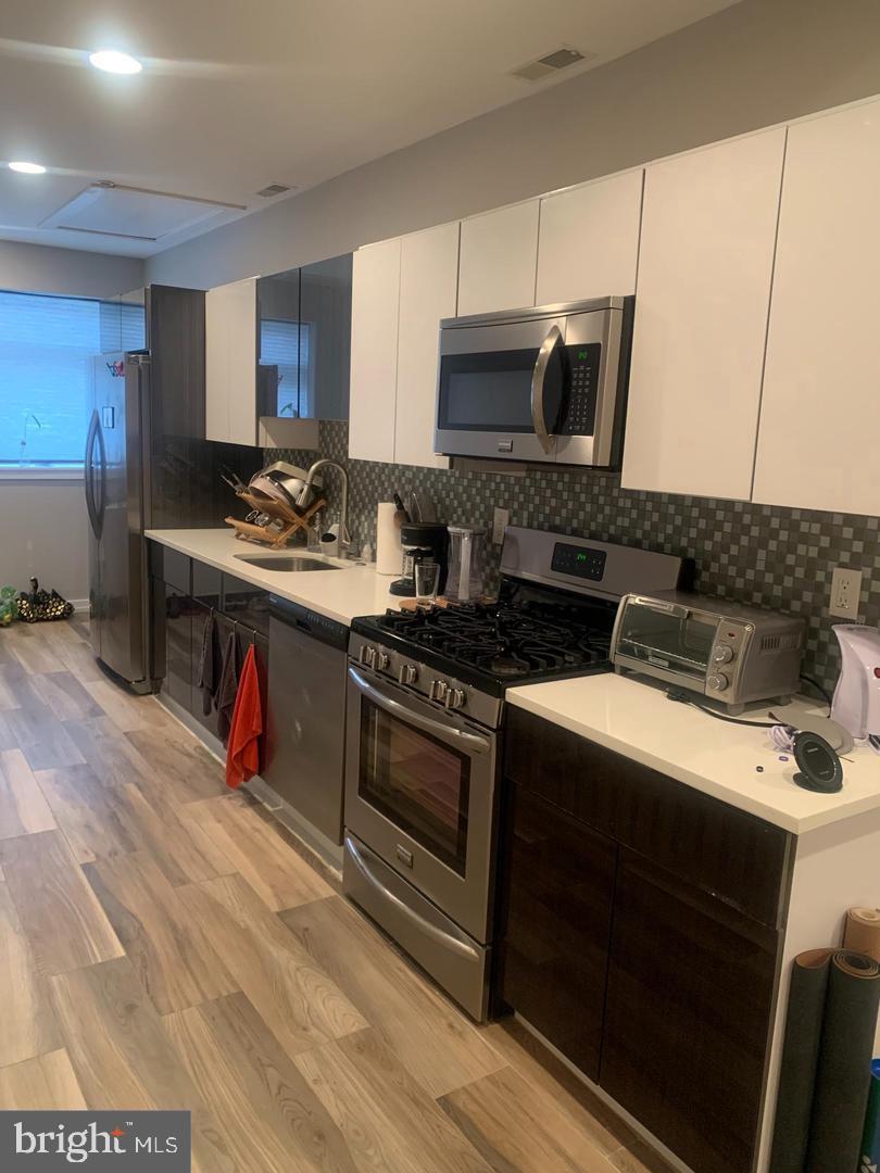 a kitchen with stainless steel appliances granite countertop a stove a sink and a microwave