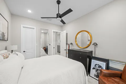 a bedroom with a bed a mirror on dresser and a chandelier