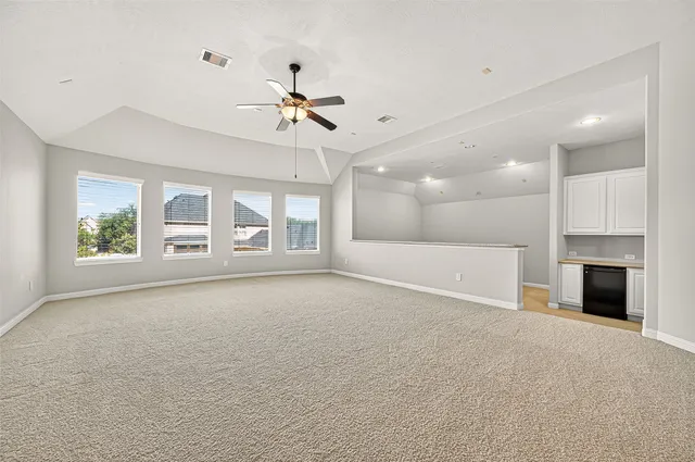 a view of an empty room with a window and a kitchen