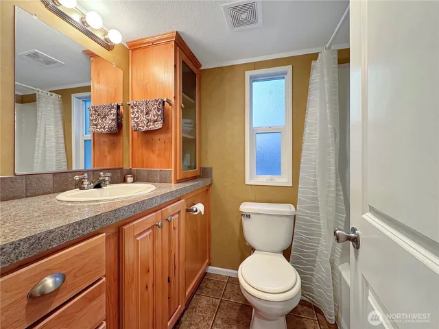 a bathroom with a granite countertop toilet sink and mirror